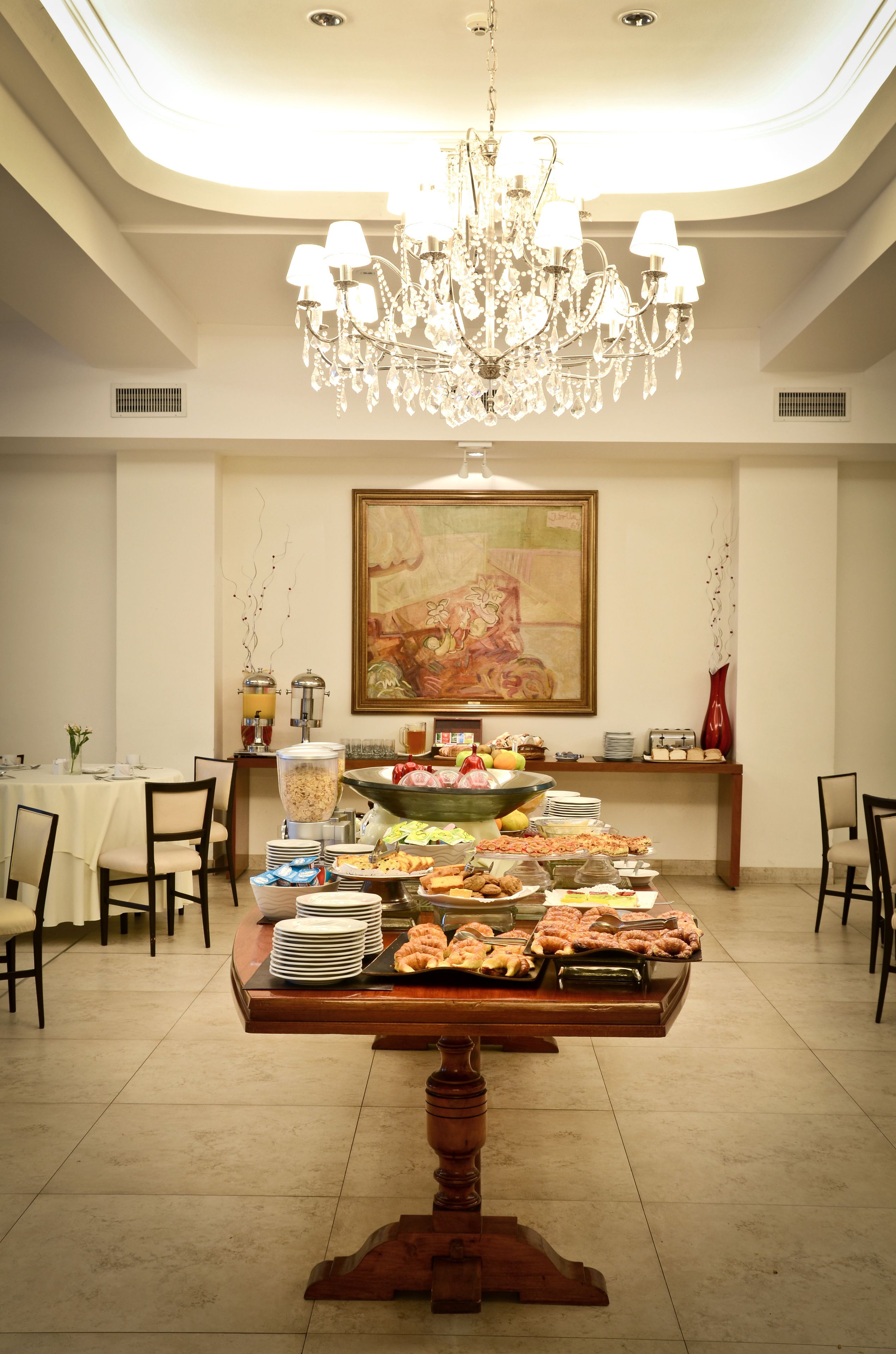 Un comedor con una mesa de buffet, una araña y un cuadro en la pared.