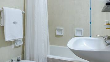 A bathroom with a toilet, bidet, bathtub, and sink.