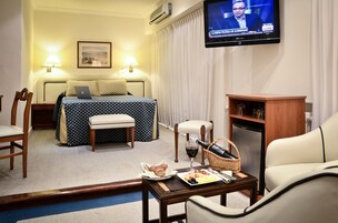 Habitación de hotel con cama, escritorio, desayuno, televisor y una silla.