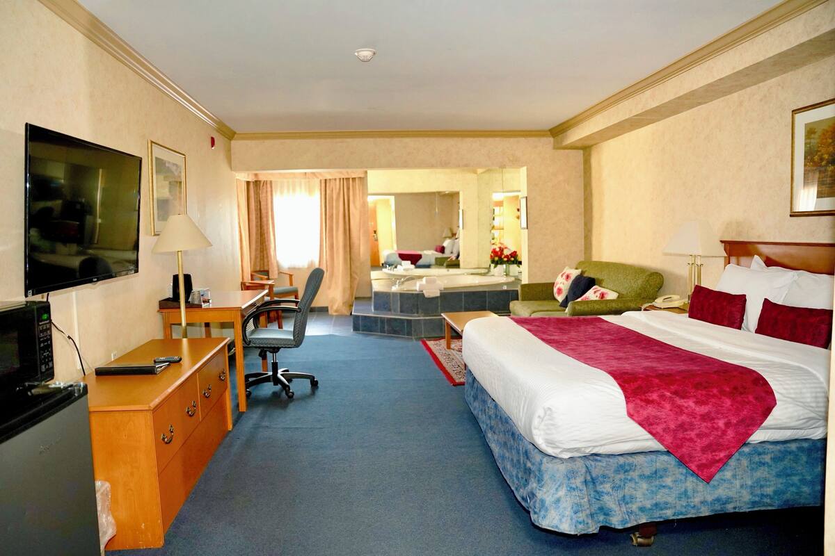 A hotel room with a bed, desk, chair, TV, and a bathroom visible through an open door.