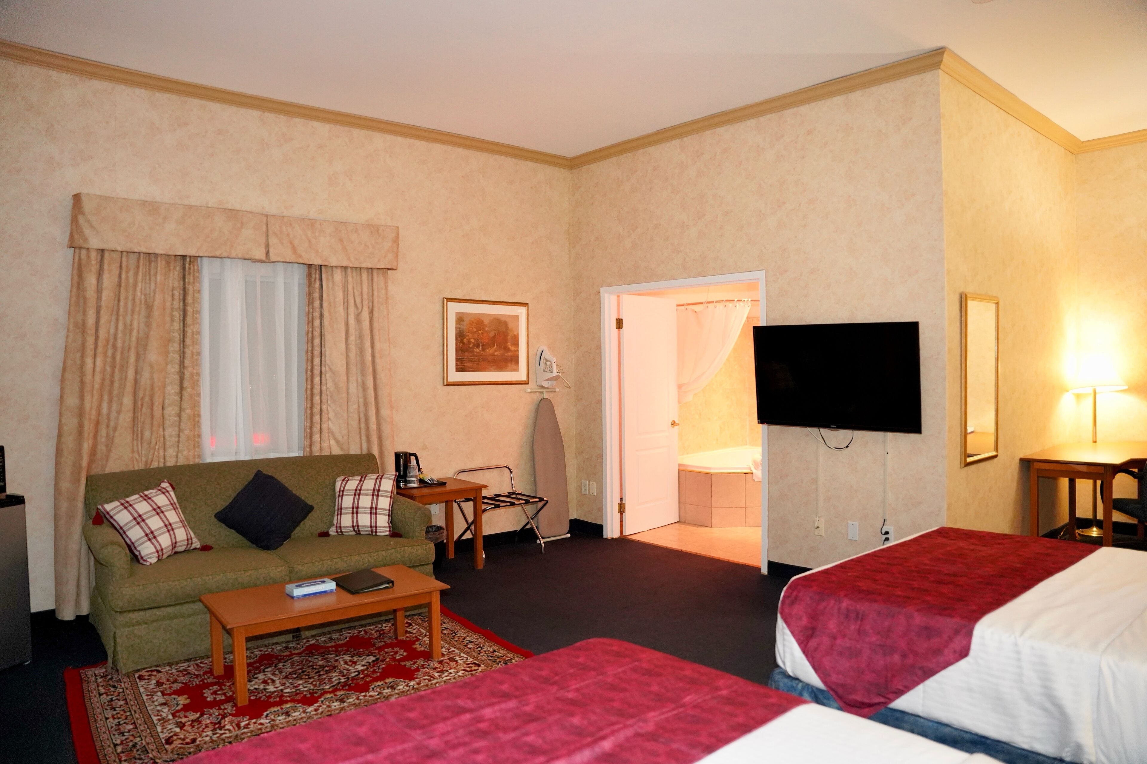 A hotel room with a sofa, a bed, a TV, a desk, and a chair.