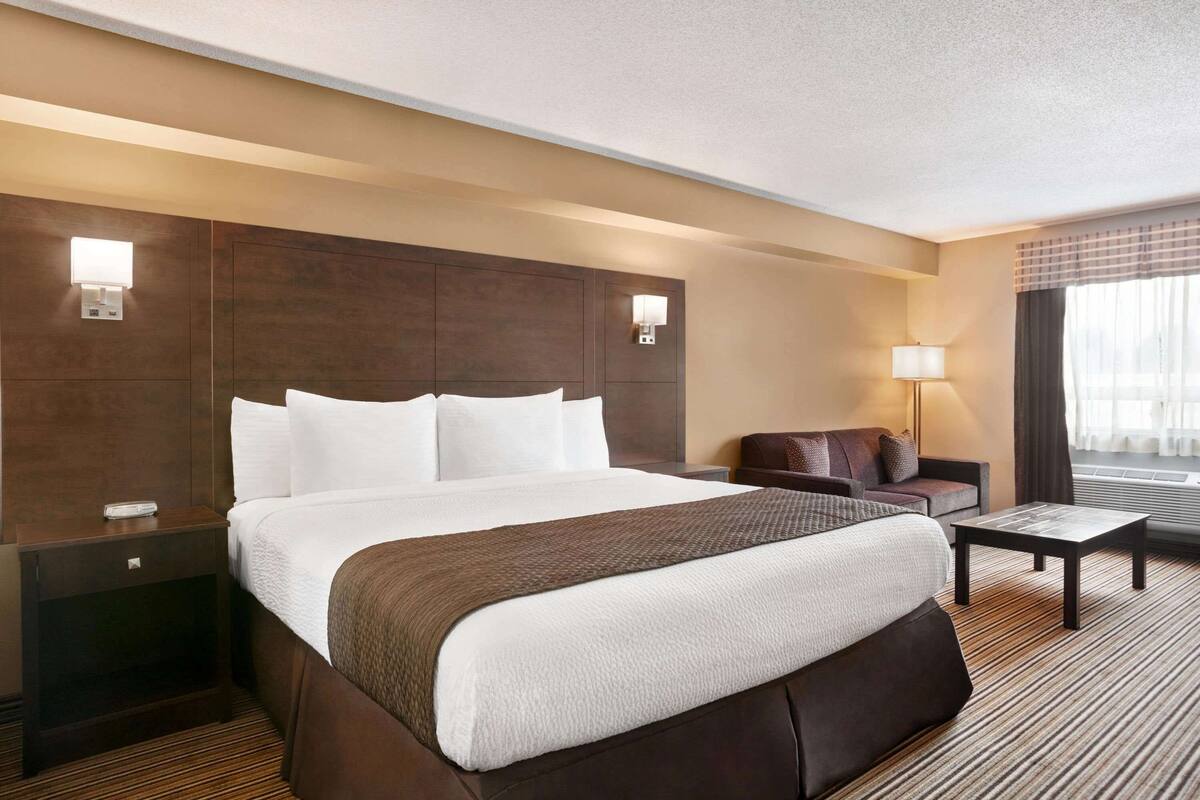 Une chambre d’hôtel avec un grand lit, un canapé, une petite table et une lampe.