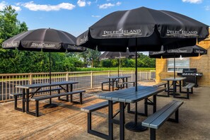 Espace extérieur aménagé avec des tables et des parasols, le tout portant l’inscription « Peelee Island Winery ».