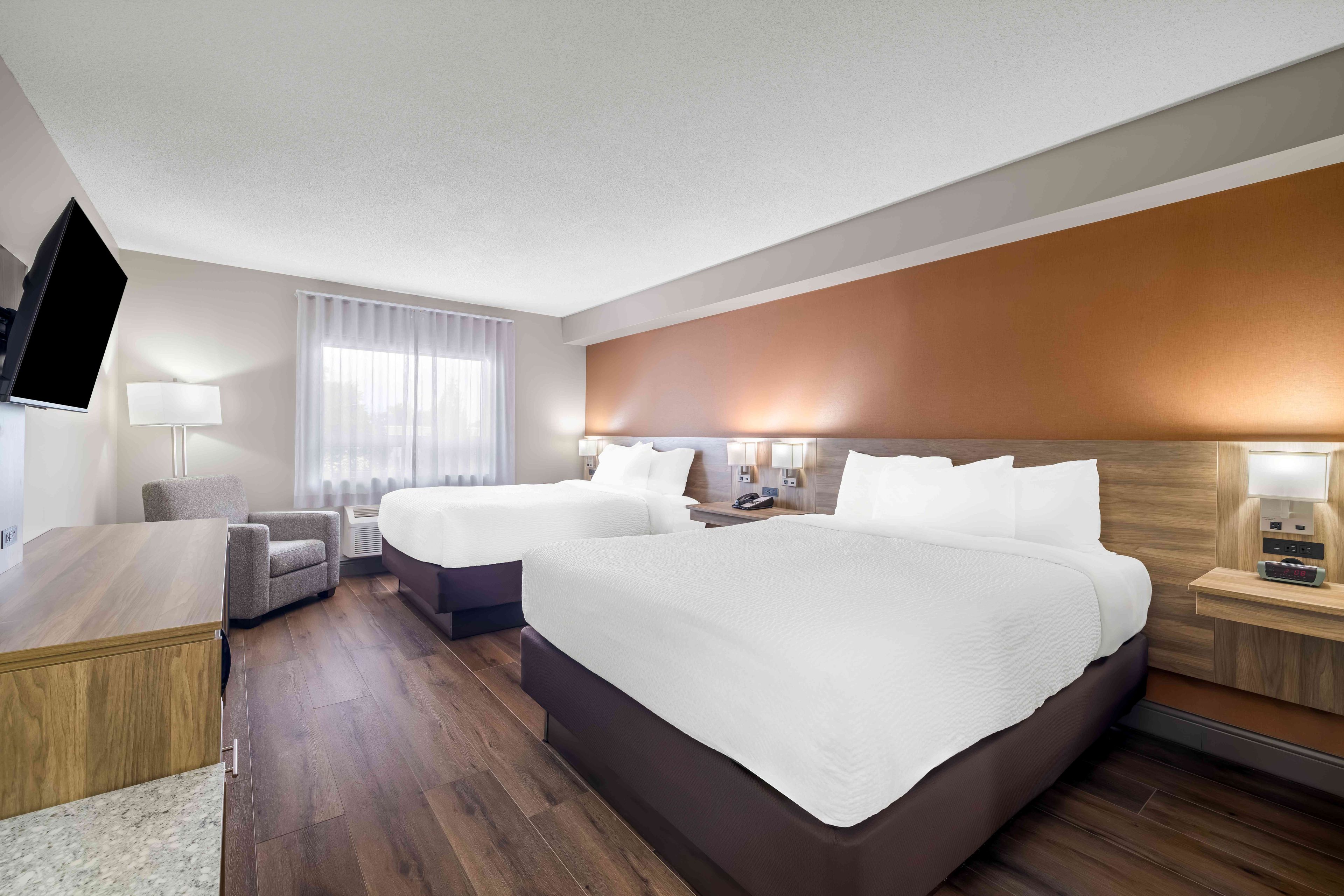 Une chambre d’hôtel avec un grand lit, un bureau, une chaise, une télévision et une table de chevet avec une lampe.