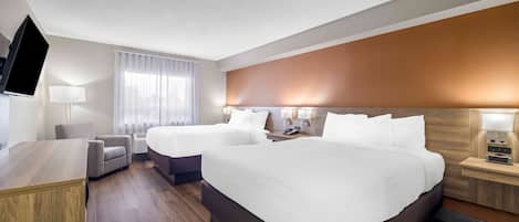 Una habitación de hotel con una cama grande, un escritorio, una silla, un televisor y una mesita de noche con una lámpara.