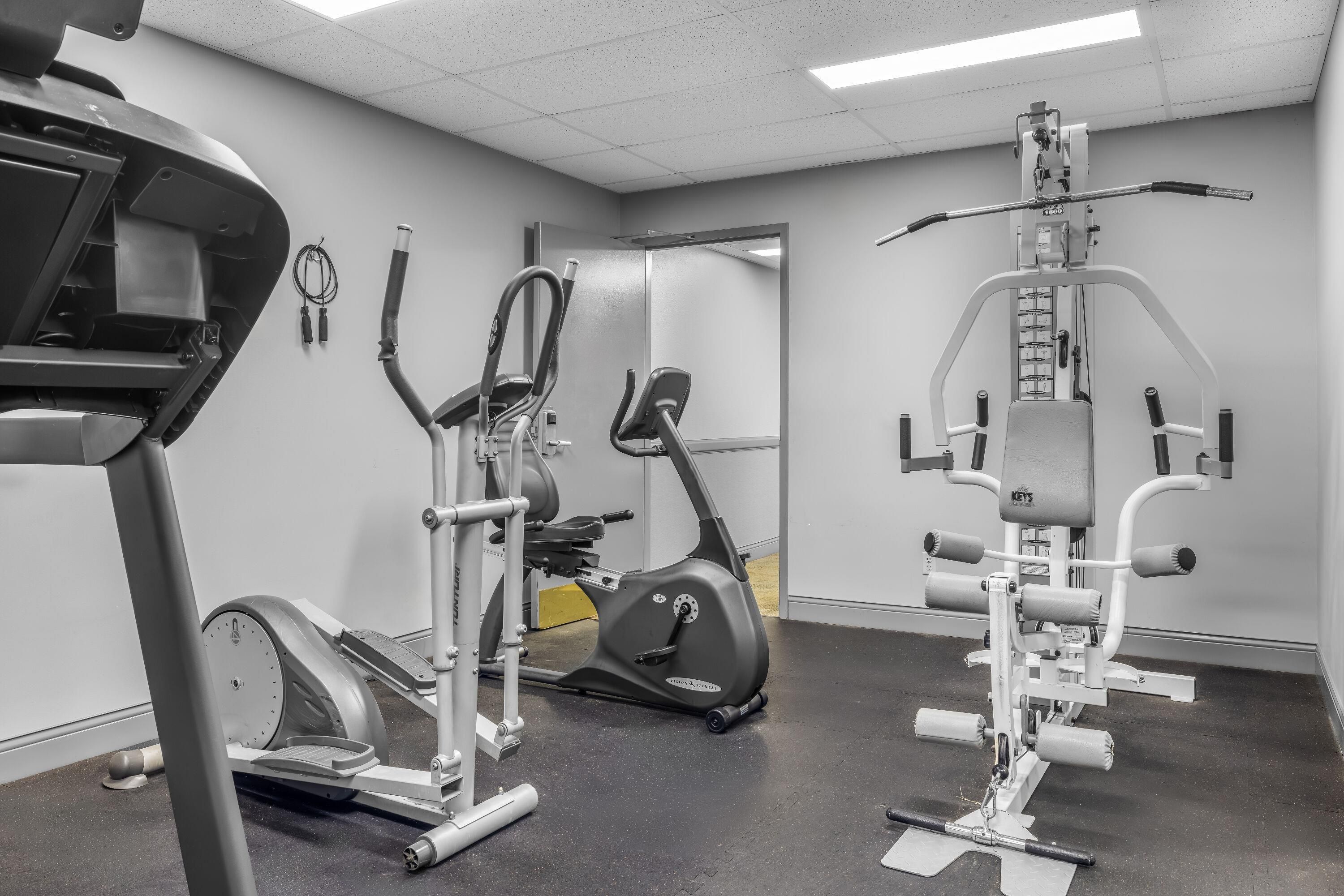 Un gimnasio con varios equipos de ejercicio, incluyendo cintas de correr, elípticas y máquinas de pesas.