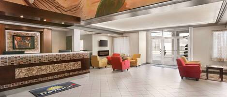A hotel lobby with a reception desk, seating area, and a mural on the ceiling.