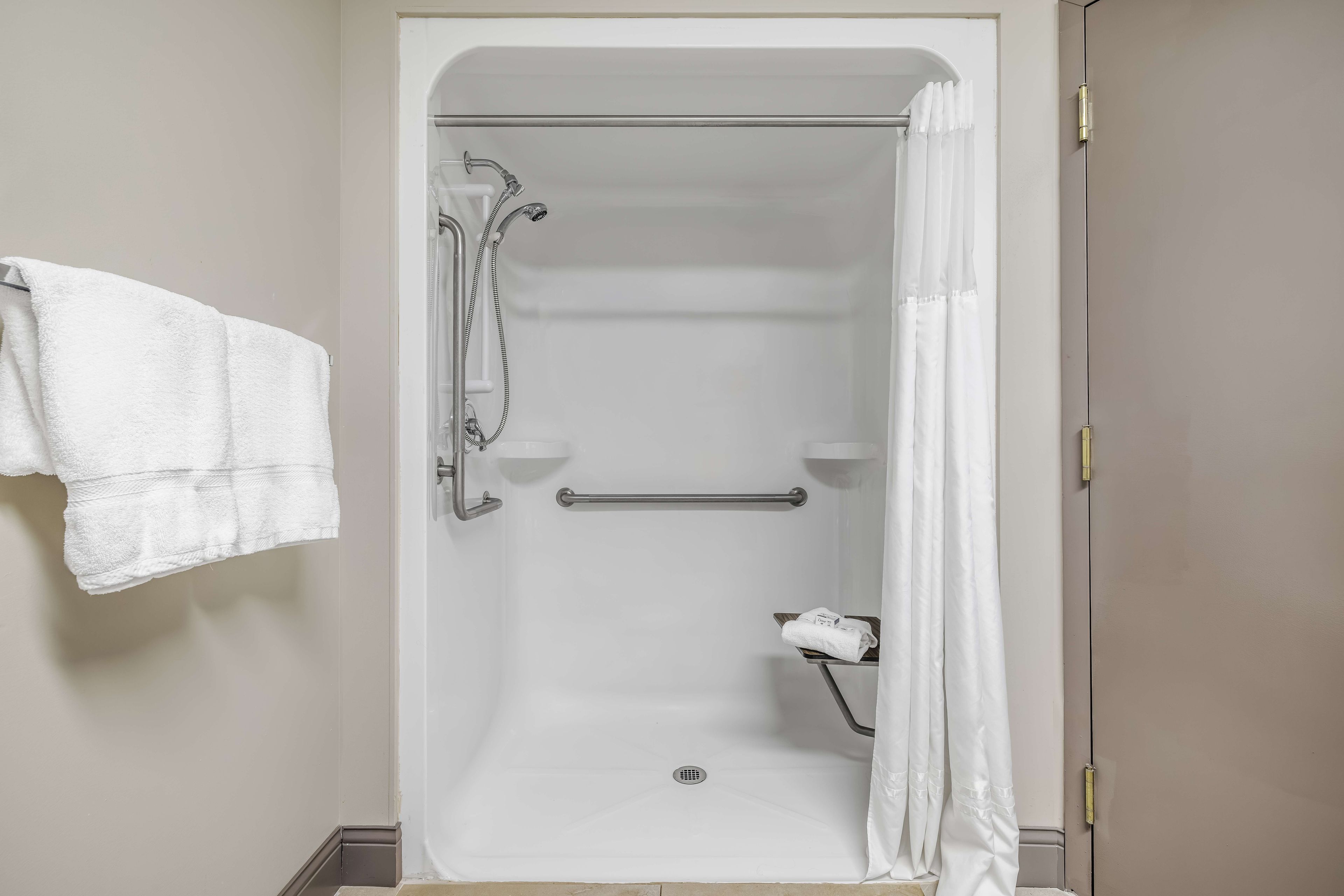 Eine begehbare Dusche mit Haltegriff, Handtuchhalter und Duschvorhang.