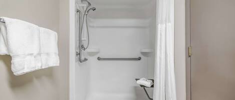 Eine begehbare Dusche mit Haltegriff, Handtuchhalter und Duschvorhang.