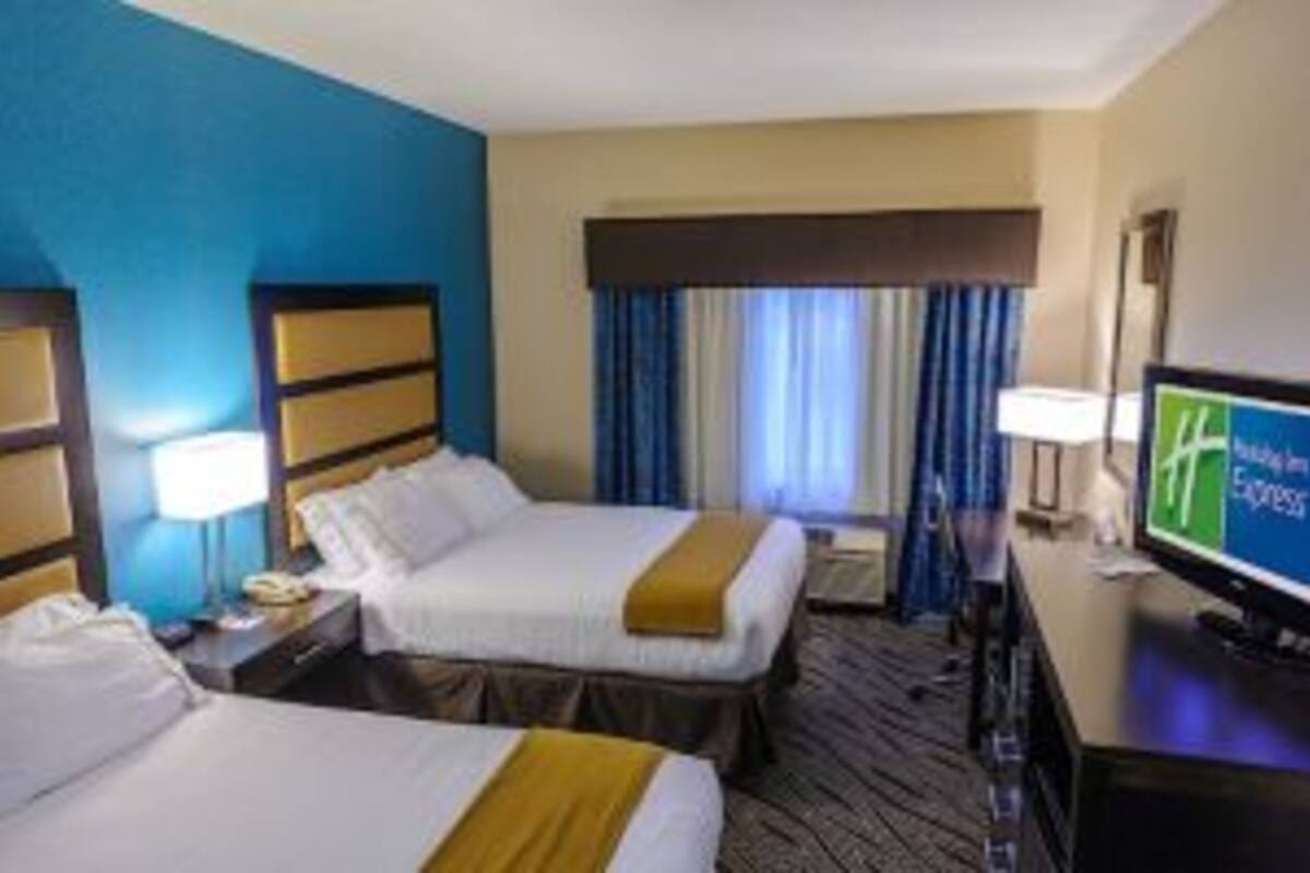 A hotel room with two beds, a TV, and a window with curtains.