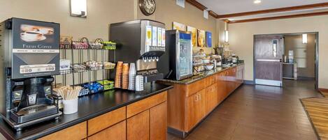 Un espace café en libre-service équipé d’une machine à café, d’un réfrigérateur et d’une variété de produits alimentaires.