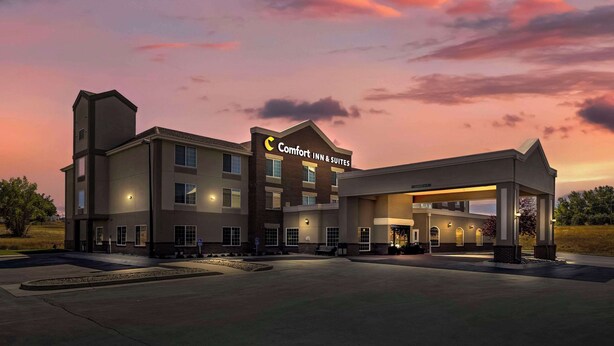 A Comfort Inn & Suites hotel with a prominent sign, a covered outdoor area, and a well-lit facade.