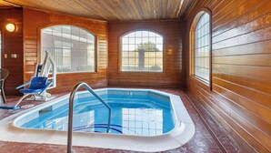 An indoor swimming pool with wooden walls and large arched windows.