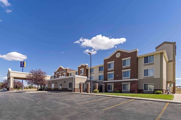 A Comfort Suites hotel with a parking lot and a clear blue sky.