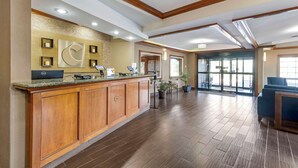 A reception area with a wooden counter, a large wall clock, and a view of the lobby.