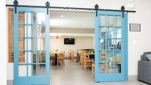 Un intérieur moderne comprenant un coin repas, des portes coulissantes bleues et un téléviseur à écran plat fixé au mur.