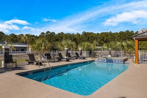 A rectangular pool with a tiled edge, surrounded by lounge chairs and a white fence. - Country Inn & Suites by Radisson, Hinesville, GA (Hinesville)