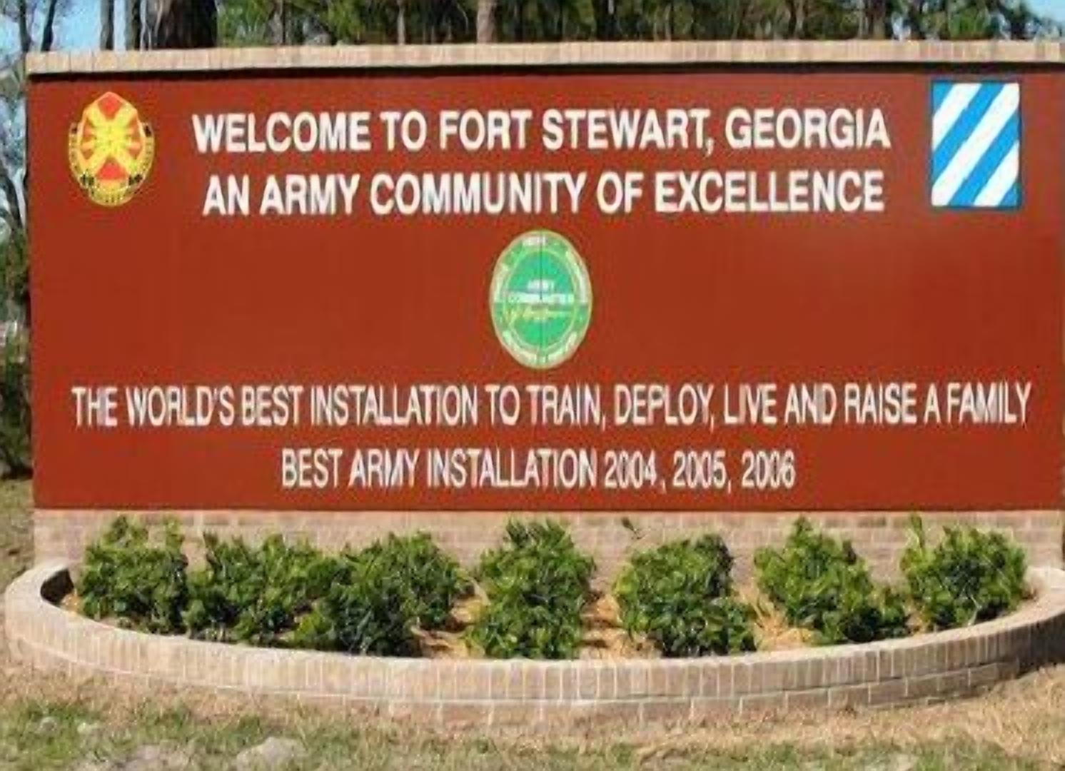 A sign welcoming visitors to Fort Stewart, Georgia, highlighting it as an army community and a top installation for training, deploying, and living.
