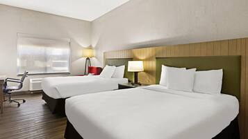 Une chambre d’hôtel avec deux lits, un bureau, une chaise et une fenêtre.