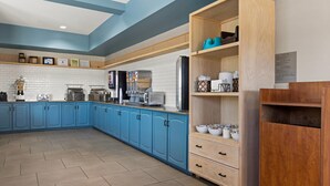 Une cuisine moderne avec des meubles de rangement bleus, un garde-manger en bois et divers appareils électroménagers.