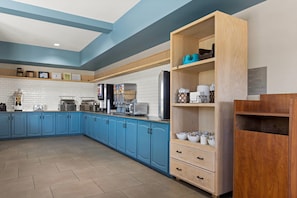 Una cocina moderna con armarios azules, una despensa de madera y varios electrodomésticos.