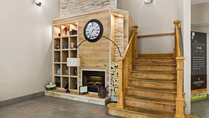 Un intérieur moderne avec un escalier en bois, une cheminée et une horloge.