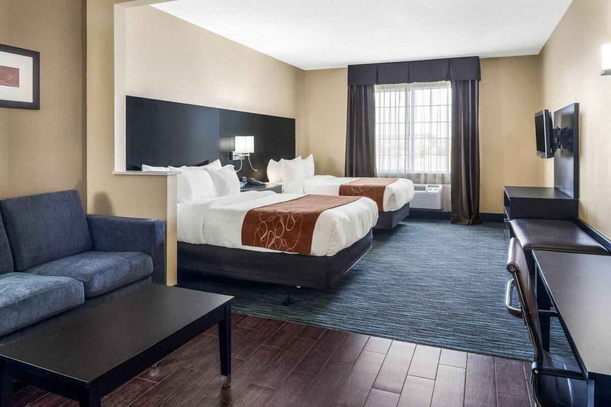 Une chambre d’hôtel avec deux lits, un canapé, un bureau, une télévision et une fenêtre avec des rideaux.