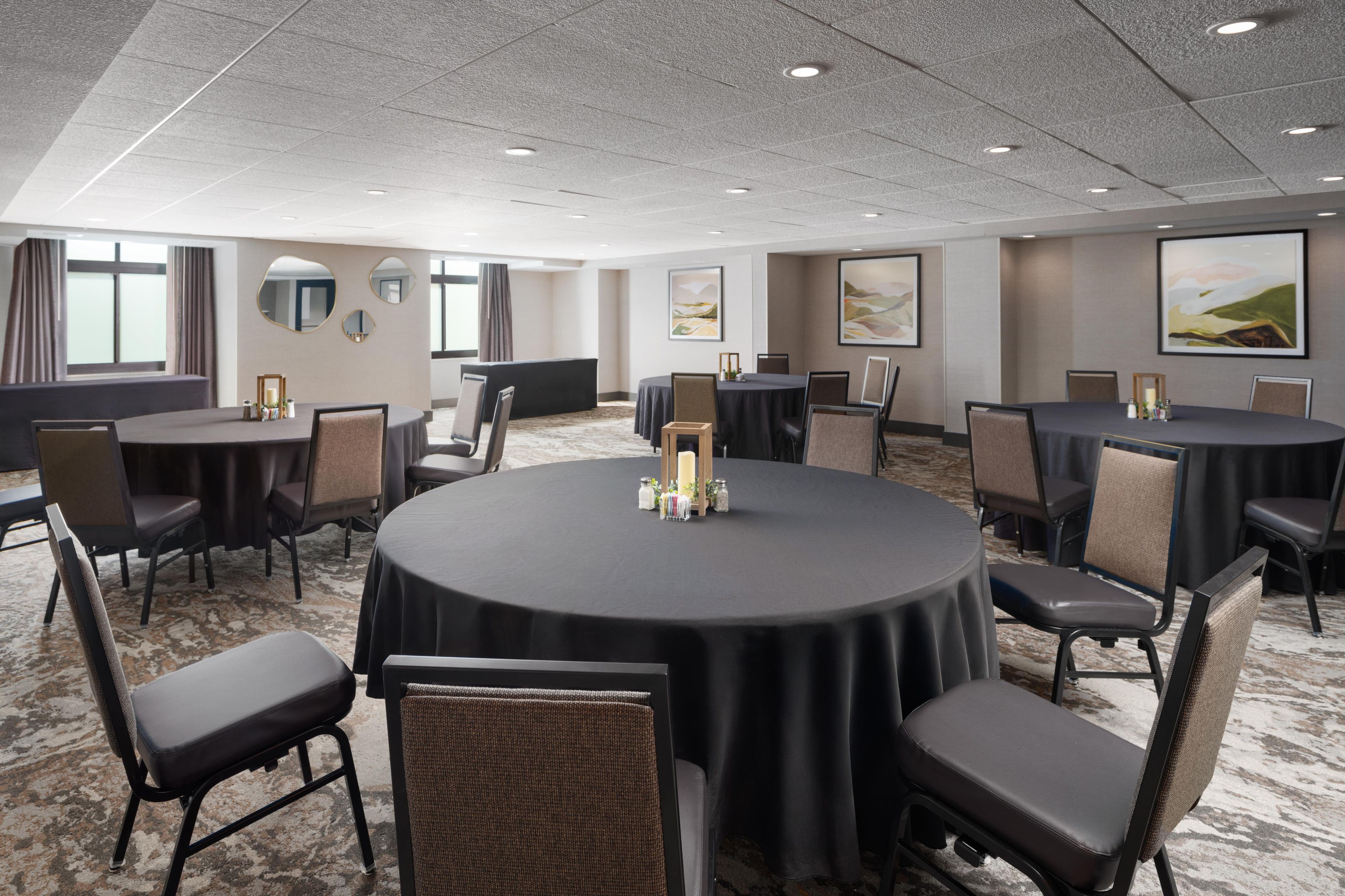 A conference room with round tables, chairs, and artwork on the walls.