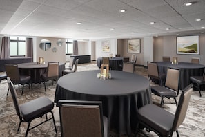 A conference room with round tables, chairs, and artwork on the walls.
