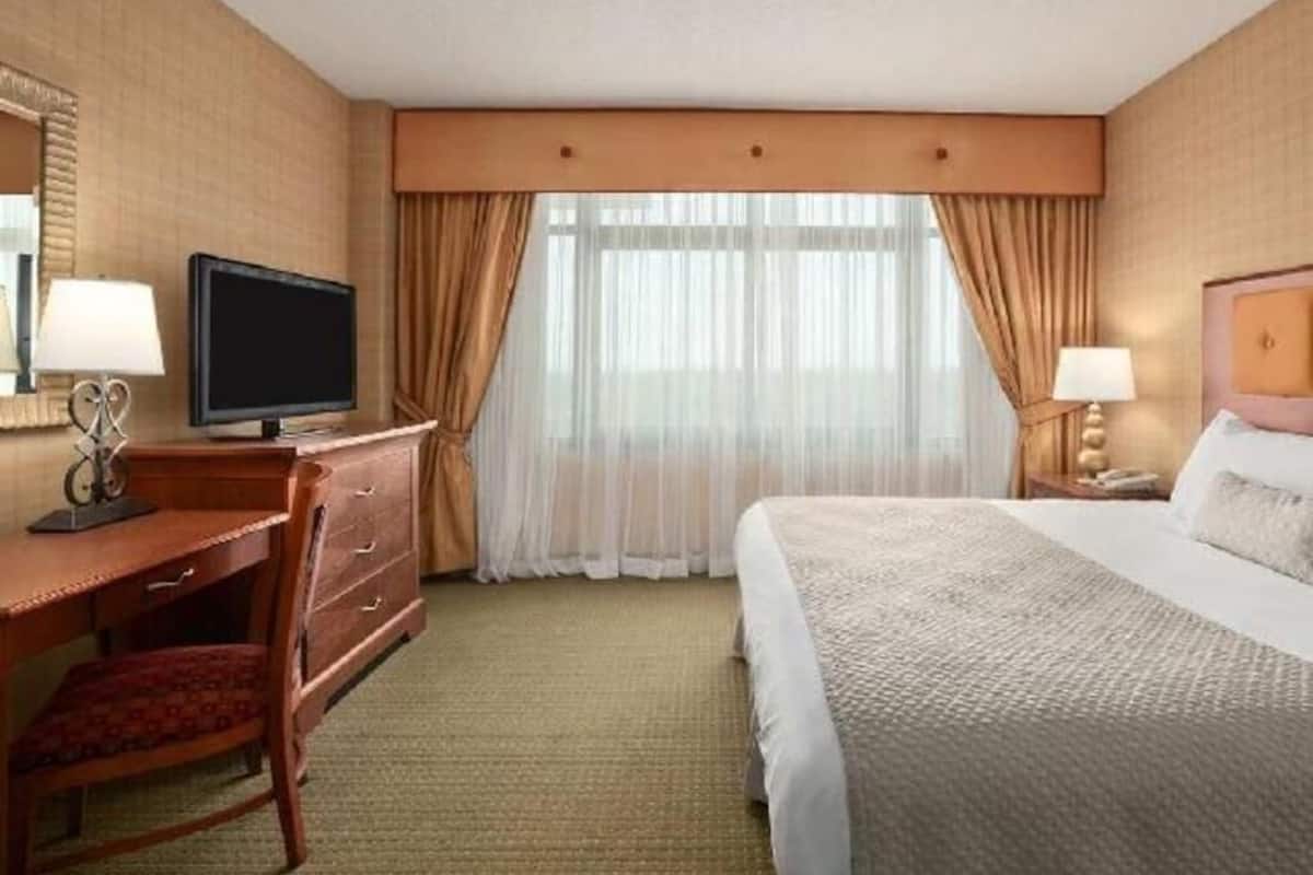 Ein Hotelzimmer mit Bett, Schreibtisch, Fernseher und Vorhängen.