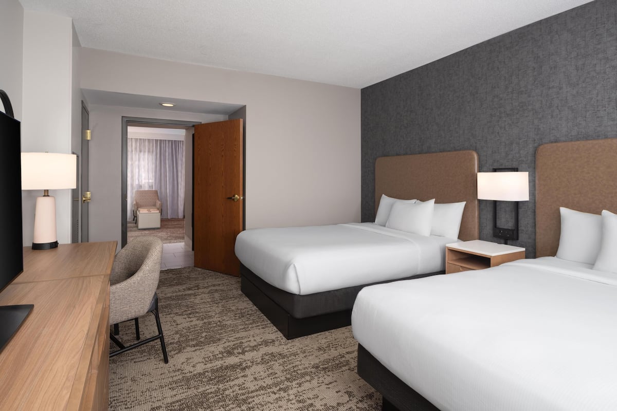 Ein Hotelzimmer mit zwei Betten, einem Schreibtisch, einem Stuhl und einem Fernseher.