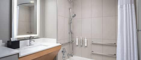 Une salle de bain moderne équipée d’une baignoire, d’une douche et d’un meuble-lavabo avec un miroir.