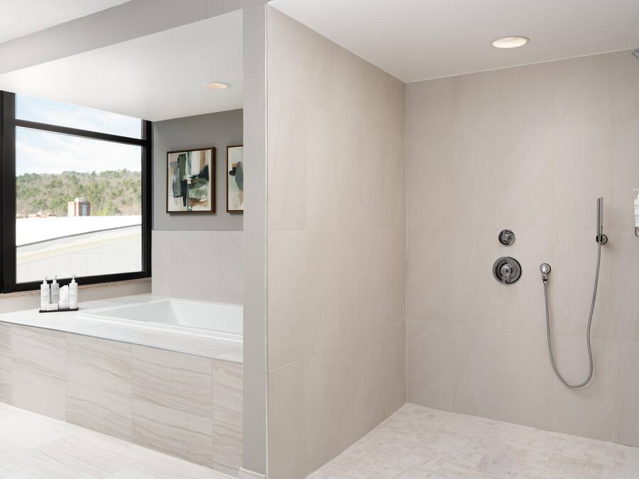 Et stilfuldt badeværelse med badekar, bruser og store vinduer.
