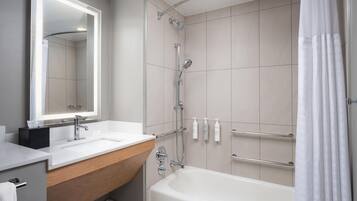 Un baño moderno con bañera, ducha, tocador con espejo y perchero.