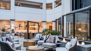 Un vaste espace intérieur aménagé avec de nombreux coins salon, un espace de restauration central et une grande fenêtre offrant une vue sur l’extérieur.