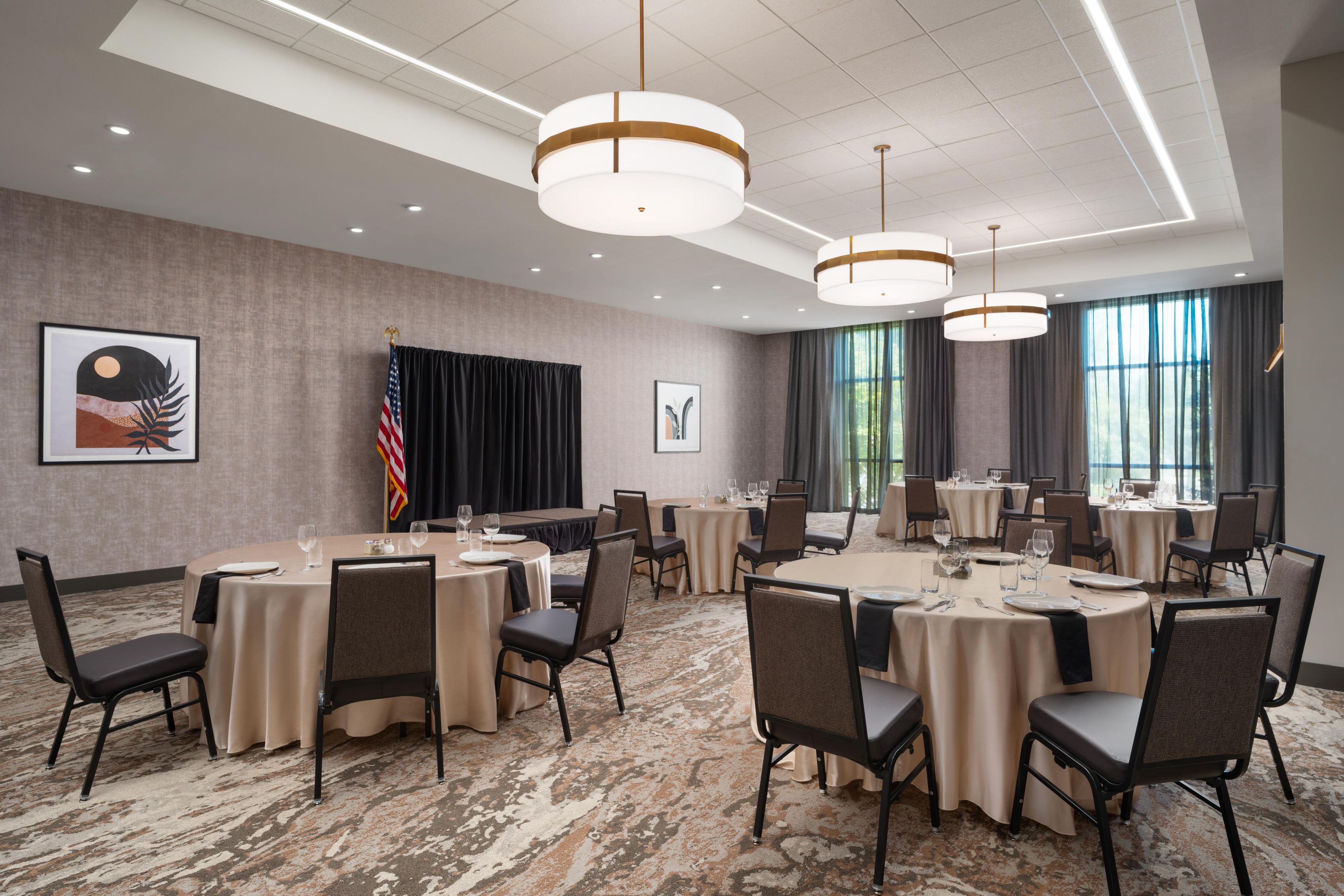 A conference room with round tables, chairs, and a flag.