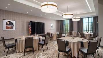 A conference room with round tables, chairs, and a flag.