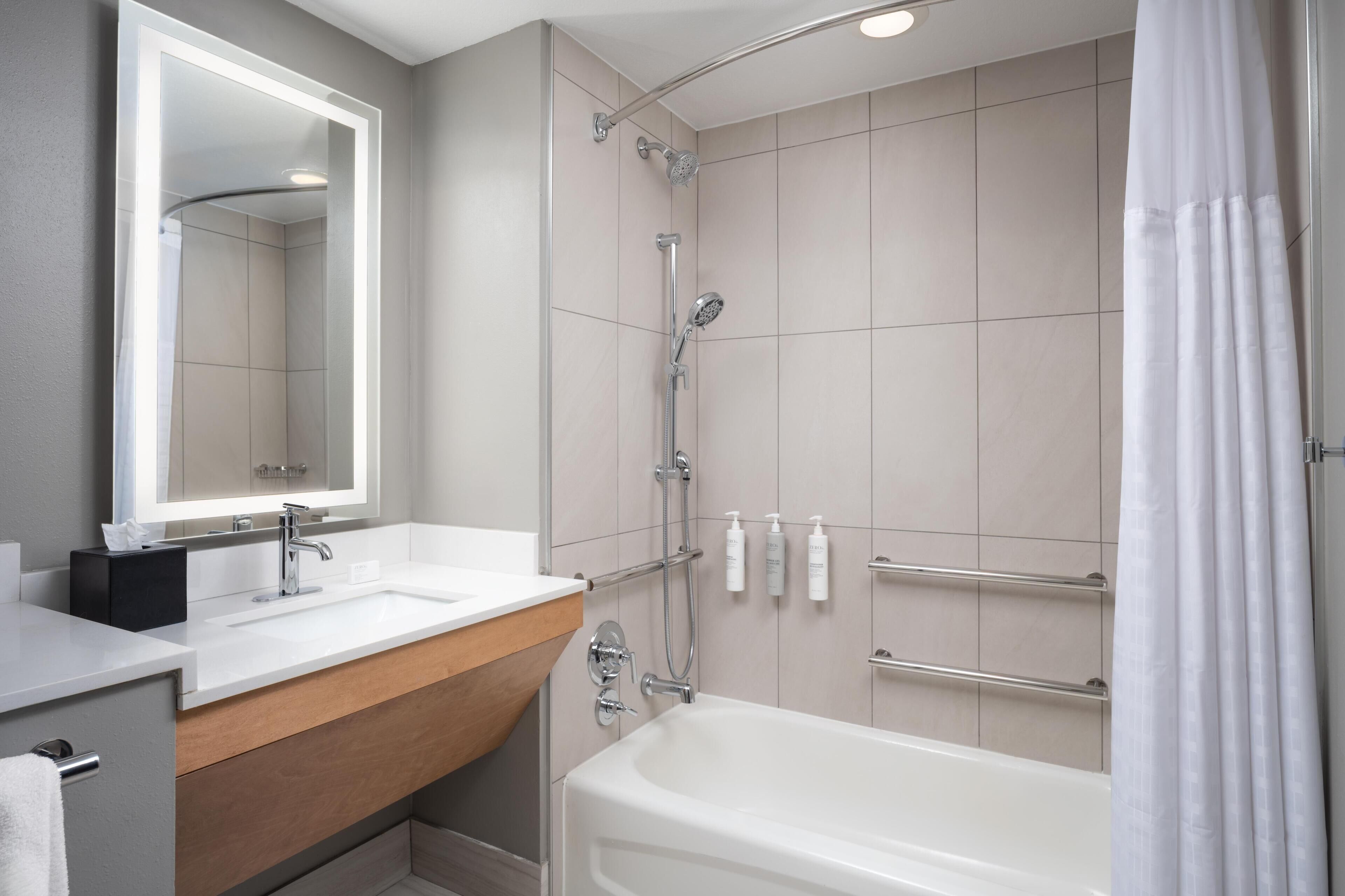 Ein modernes Badezimmer mit Waschbecken, Spiegel, Dusche und Badewanne.
