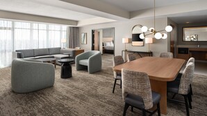 Une chambre d’hôtel comprenant un espace salon, une table à manger et une chambre à coucher séparée.