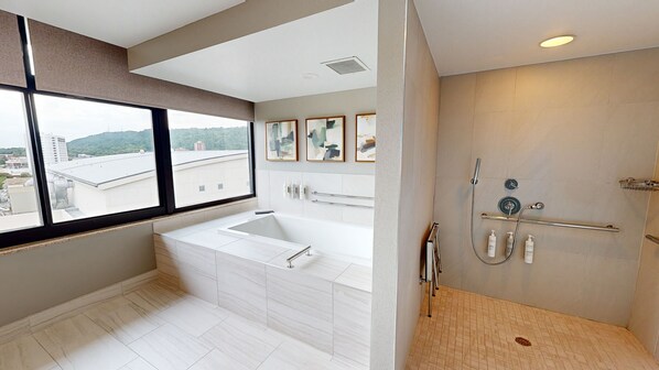 A modern bathroom with a large bathtub, a shower area, and a window with a city view.