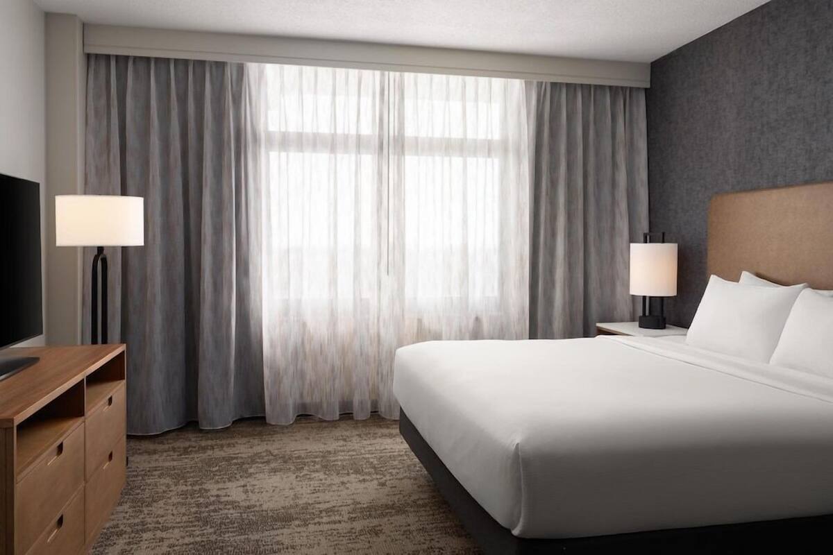 Een hotelkamer met een groot bed, twee bedlampen, een televisie en een bureau.