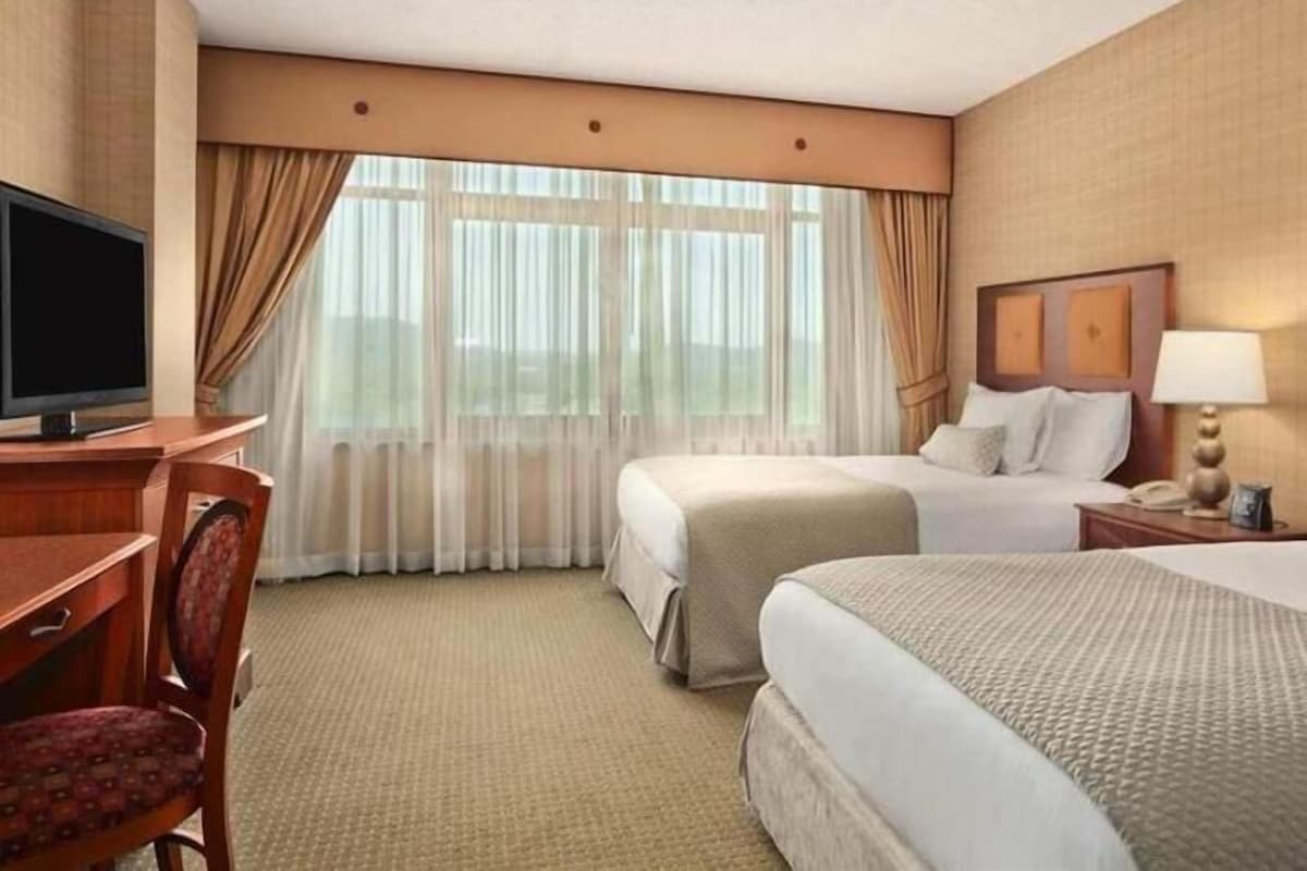 Une chambre d’hôtel équipée d’une télévision, de deux lits, d’un bureau et d’une chaise.