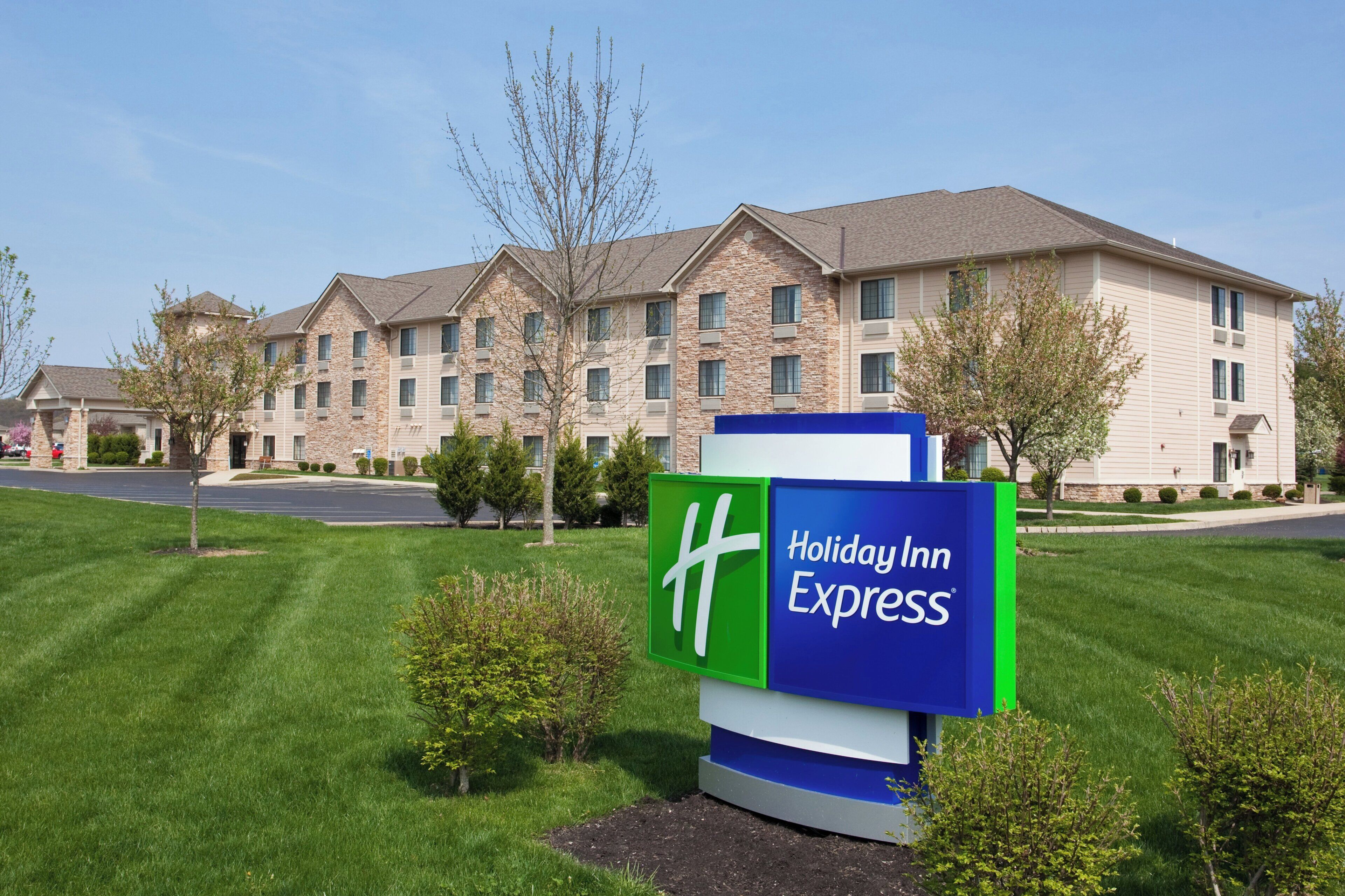 Une enseigne Holiday Inn Express devant un immeuble à plusieurs étages, doté d’une façade en pierre et de nombreuses fenêtres.