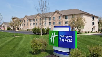 Une enseigne Holiday Inn Express devant un immeuble à plusieurs étages, doté d’une façade en pierre et de nombreuses fenêtres.
