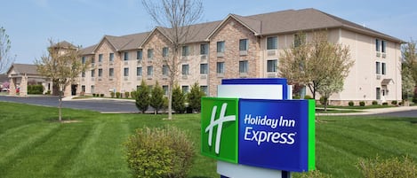Une enseigne Holiday Inn Express devant un immeuble à plusieurs étages, doté d’une façade en pierre et de nombreuses fenêtres.