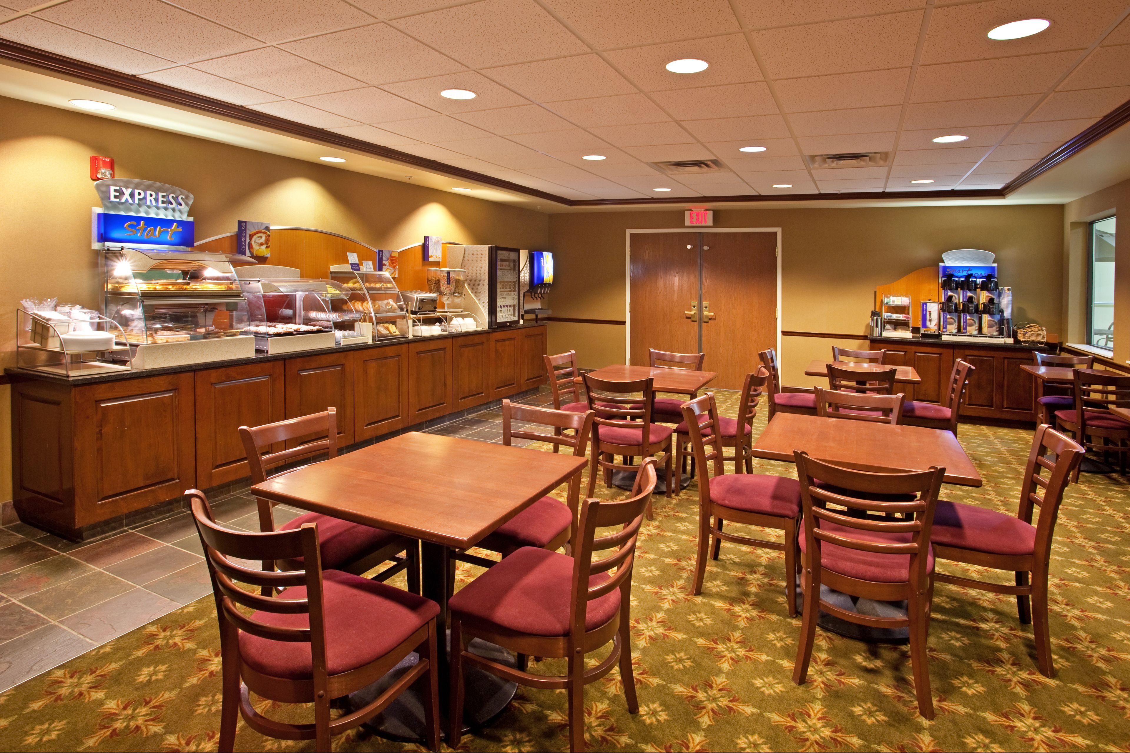 A hotel dining area with multiple tables and chairs, a buffet counter, and a coffee station.