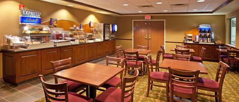 Comedor de hotel con varias mesas y sillas, un mostrador de buffet y una estación de café.