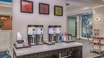 A reception area with a counter, coffee machines, and framed artwork on the wall.