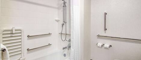 Ein Badezimmer mit einer weißen Badewanne, einer Dusche inklusive Handbrause, einer Toilette und einem Handtuchhalter.