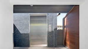 Un ascensor con interior metálico y paredes de mármol.